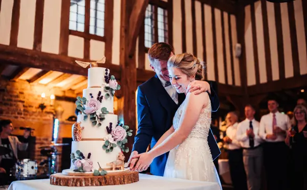 bride and groom cutting their wedding cake under the beams of The Gallery