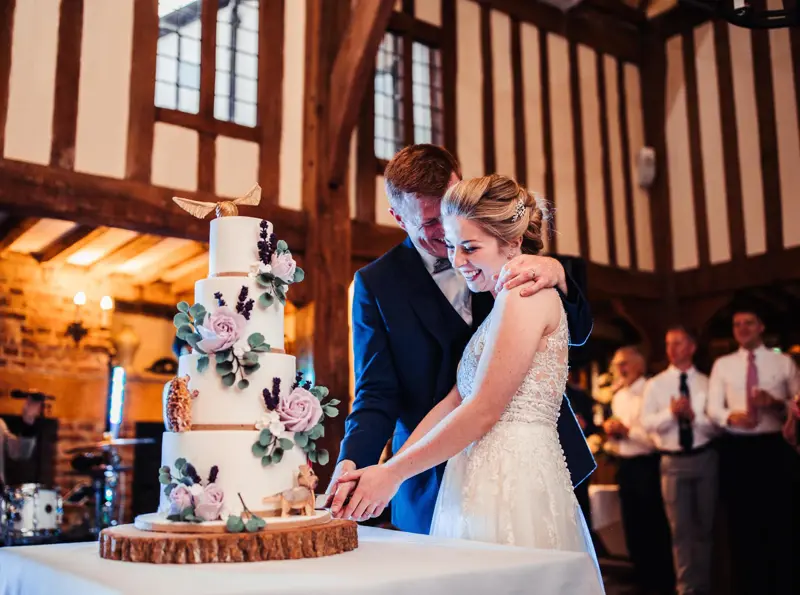 Bride and Groom cutting into their wedding cake under the beams of The Gallery