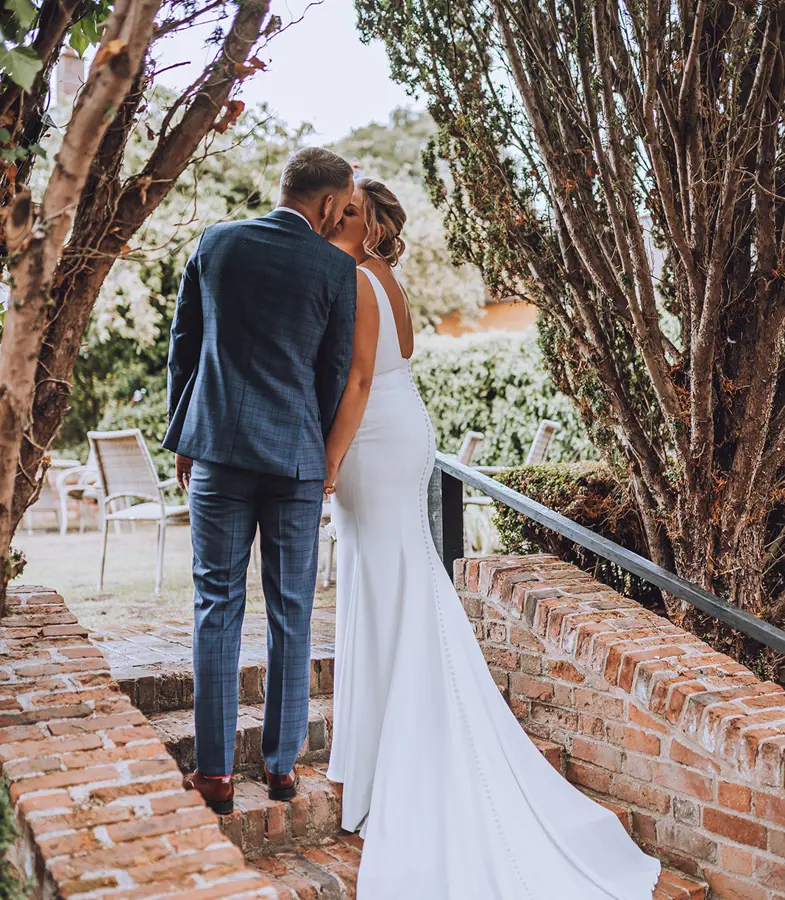 Bride and Groom kissing on steps leading to The Swan's secret garden with dress trailing behind