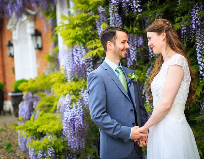 Swan at Lavenham Hotel & Spa - Weddings - couple next to wisteria tree purple flowers