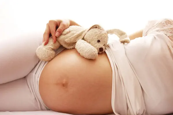 Baby bump with a teddy bear resting on top