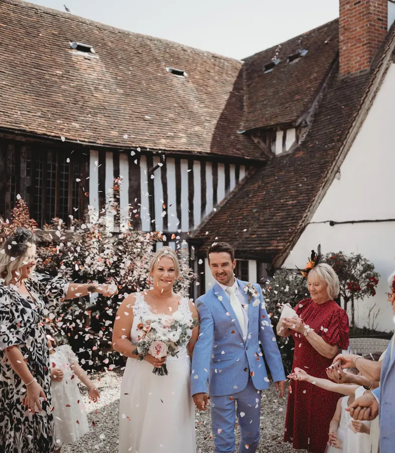 Emma and Mike - family throwing confetti over bride and groom in the courtyard on a sunny day