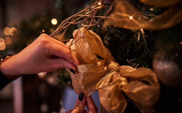 Tying festive bow on Christmas Tree