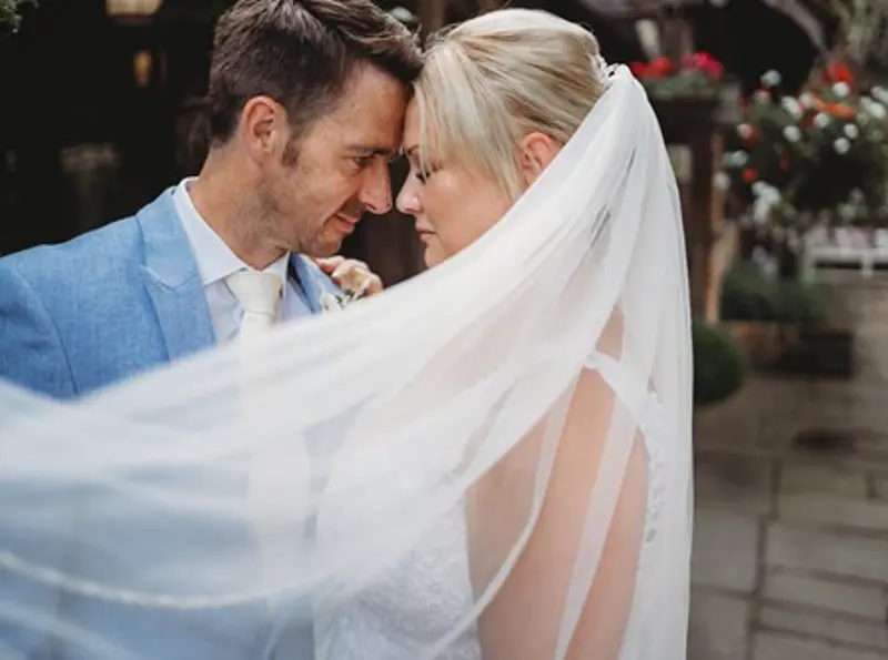 Bride and Groom holding one another with veil flowing across